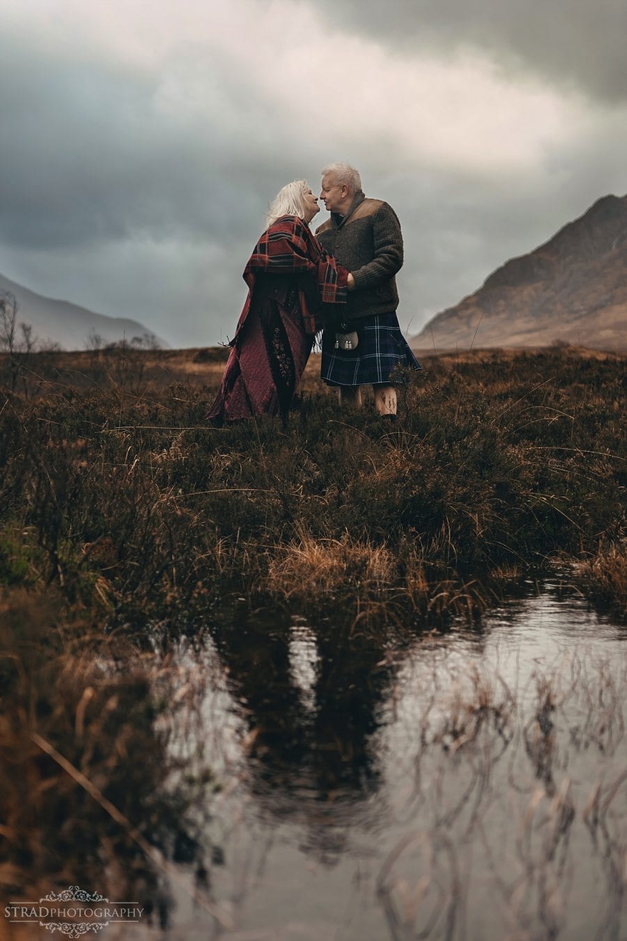 beautiful scenery, deers, elderly couple, engagement photography, glasgow photographer, glen etive, Glencoe, grandma, grandpa, hiking, kilt, landscapes, man and woman, marr, marriage, old couple, old married couple, older couple photo shoot in Glencoe Scotland, outlander, poncho, posing ideas, scotland, scottish couple, scottish highlands, senior couple, tartan