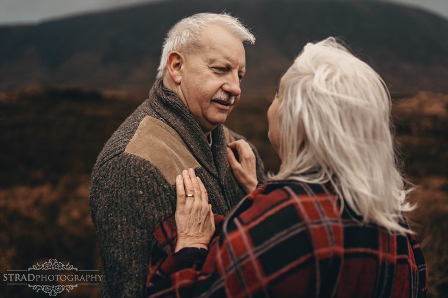 beautiful scenery, deers, elderly couple, engagement photography, glasgow photographer, glen etive, Glencoe, grandma, grandpa, hiking, kilt, landscapes, man and woman, marr, marriage, old couple, old married couple, older couple photo shoot in Glencoe Scotland, outlander, poncho, posing ideas, scotland, scottish couple, scottish highlands, senior couple, tartan