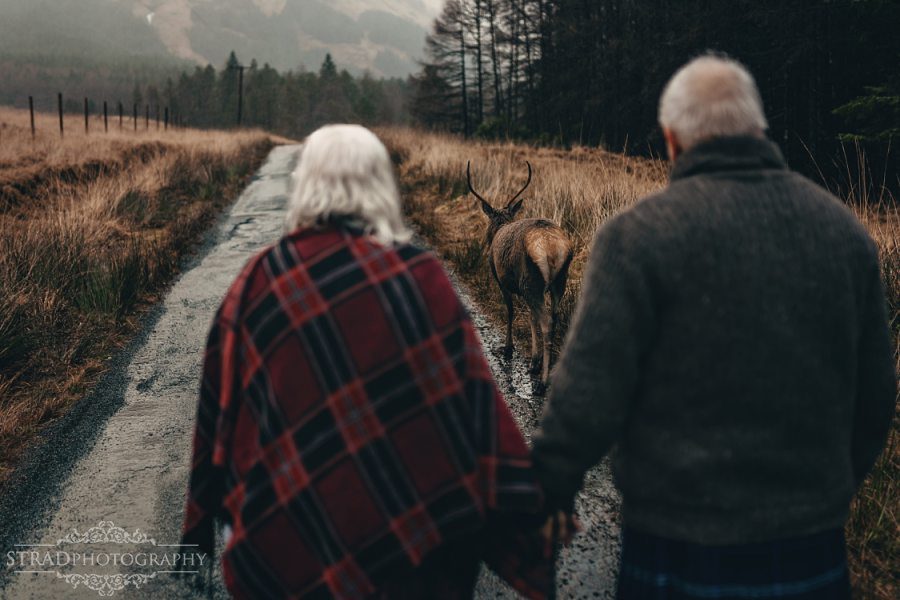 beautiful scenery, deers, elderly couple, engagement photography, glasgow photographer, glen etive, Glencoe, grandma, grandpa, hiking, kilt, landscapes, man and woman, marr, marriage, old couple, old married couple, older couple photo shoot in Glencoe Scotland, outlander, poncho, posing ideas, scotland, scottish couple, scottish highlands, senior couple, tartan