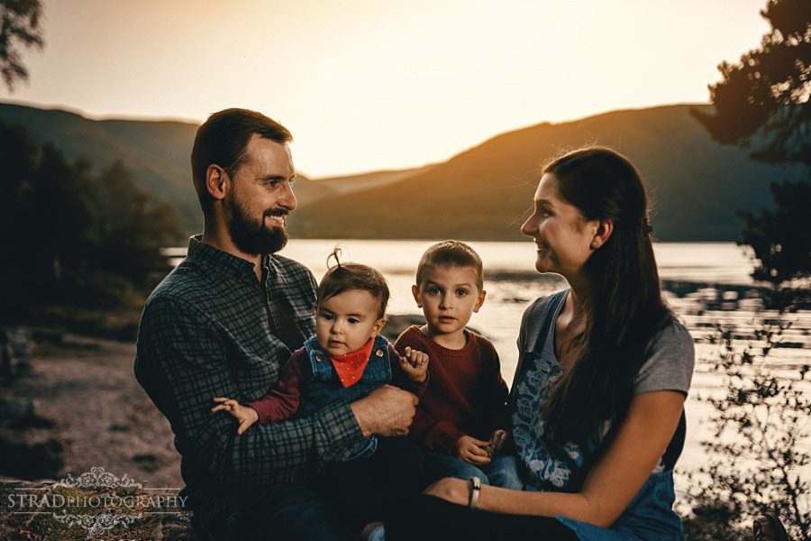 a family of 4 sitting at the loch lomond during sunset