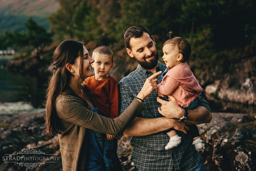a family of 4 sitting at the loch lomond during sunset