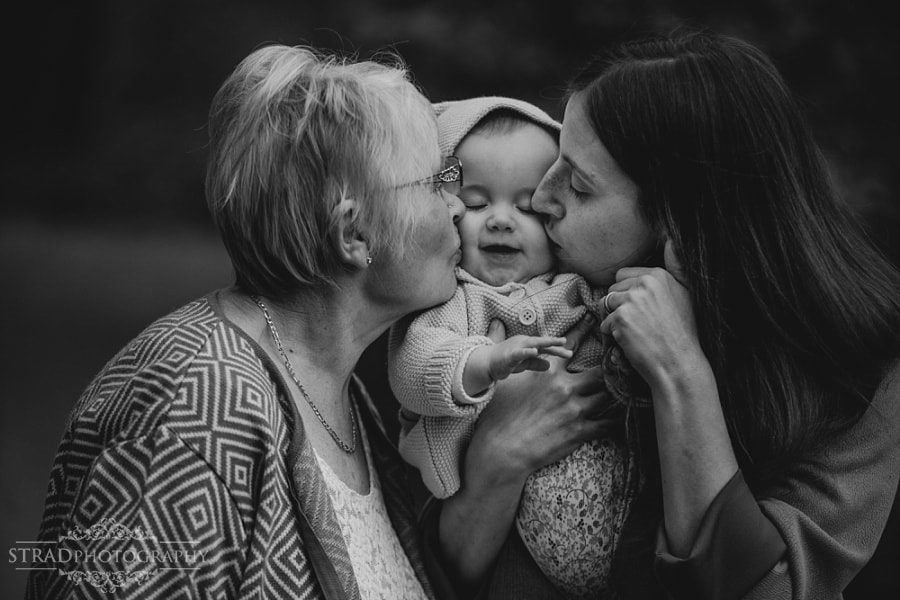 Mother and Grand mother kisses little girl in the cheek