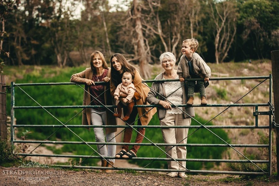 Portrait of 4 generation of women standing on the fence