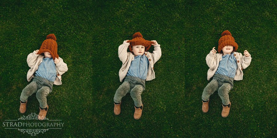 Cute portrait of a young boy in a ginger hat laying on the grass