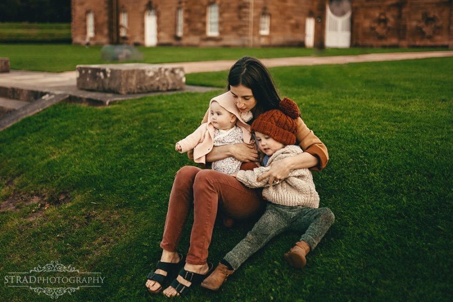 Mother with her kids sitting the grass in front of the visitor centre in Chatelherault Country Park