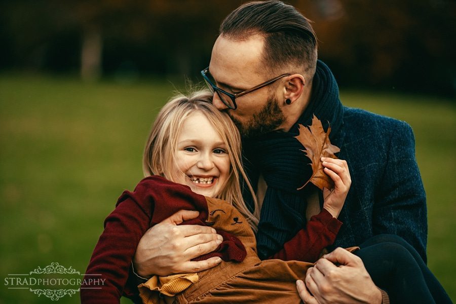 Father holding his daughter in the arms and kissing her in the head