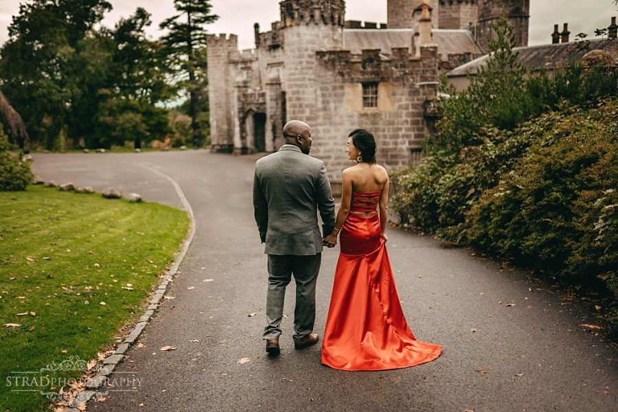 Woman in red dress walks with her husband around Balloch Castle