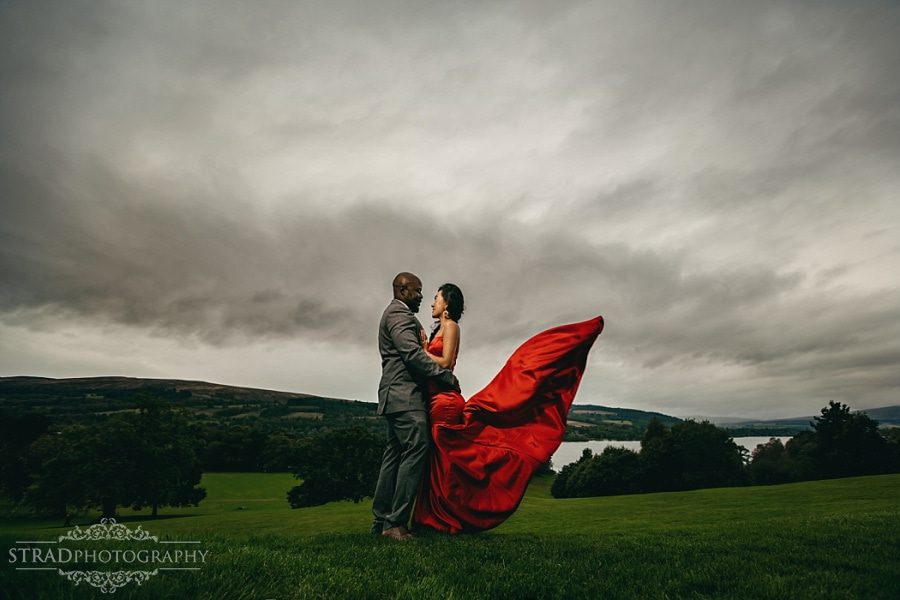 Dramatic photo of the bride in red dress and the groom in front of the Balloch Castle