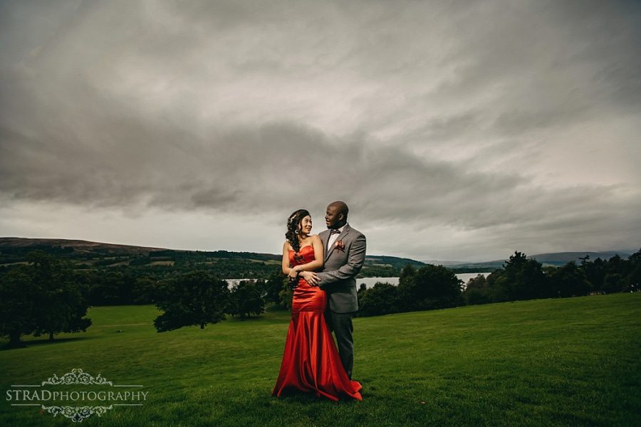 Dramatic photo of the bride in red dress and the groom in front of the Balloch Castle