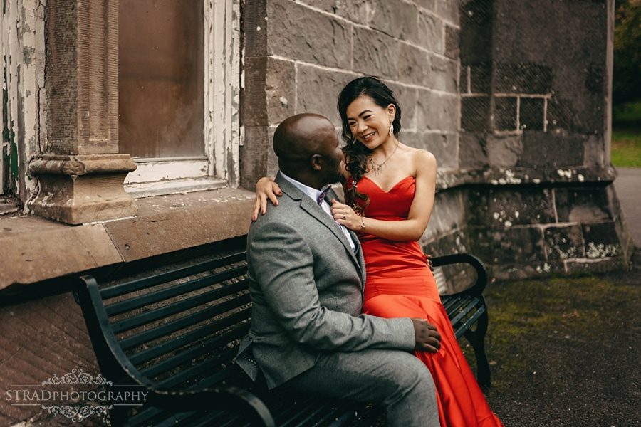Bride in the red dress sitting on the grooms lap