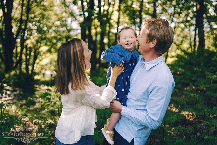 Mum and dad tickle their daughter.