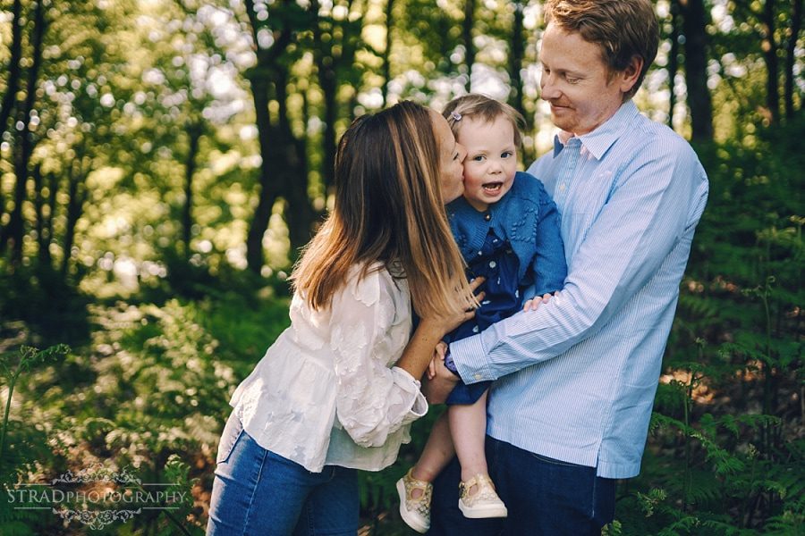 Mum kisses her daughter who is held by the father