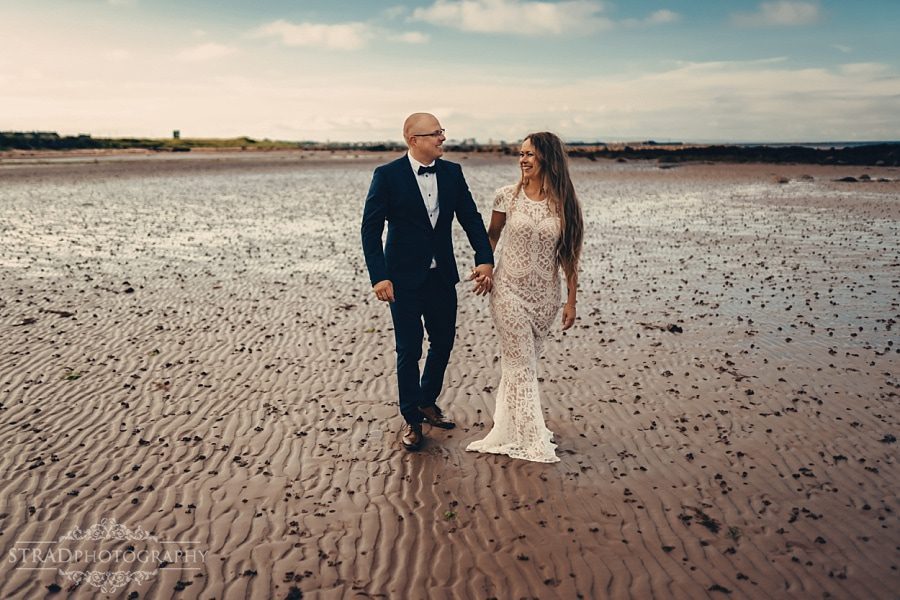 Wedding couple holding hands while walking at the beach near Ardrossan,