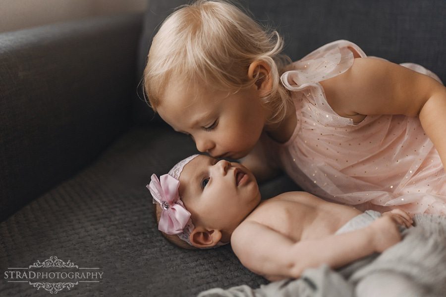 Little girl kisses her newborn sister