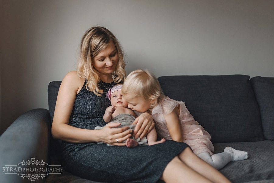 Little girl kisses her newborn sister