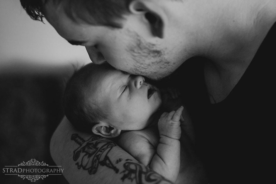 father holds his newborn daughter in his arms and kisses her