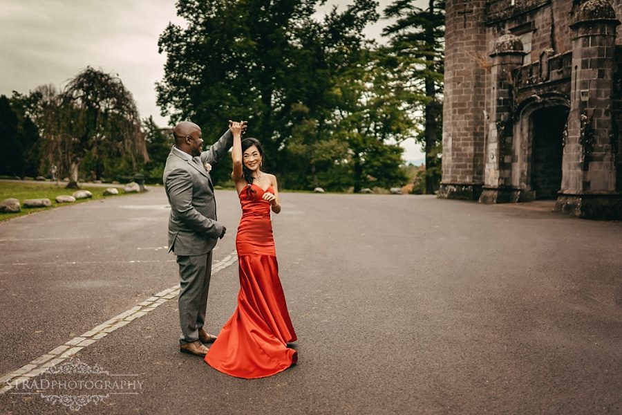 Woman in red dress dances with her husband next to Balloch Castle
