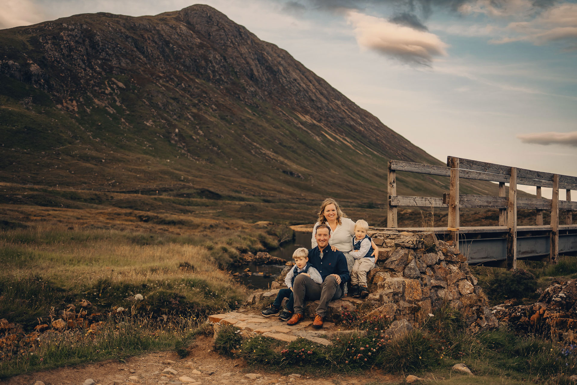 family sitting on next to the bridge