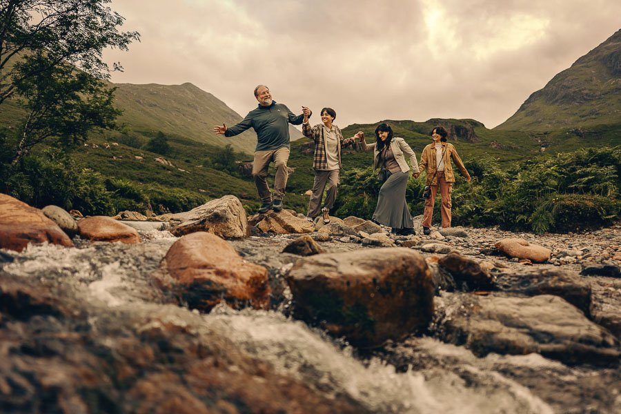 Group crossing a rocky riverbank together.