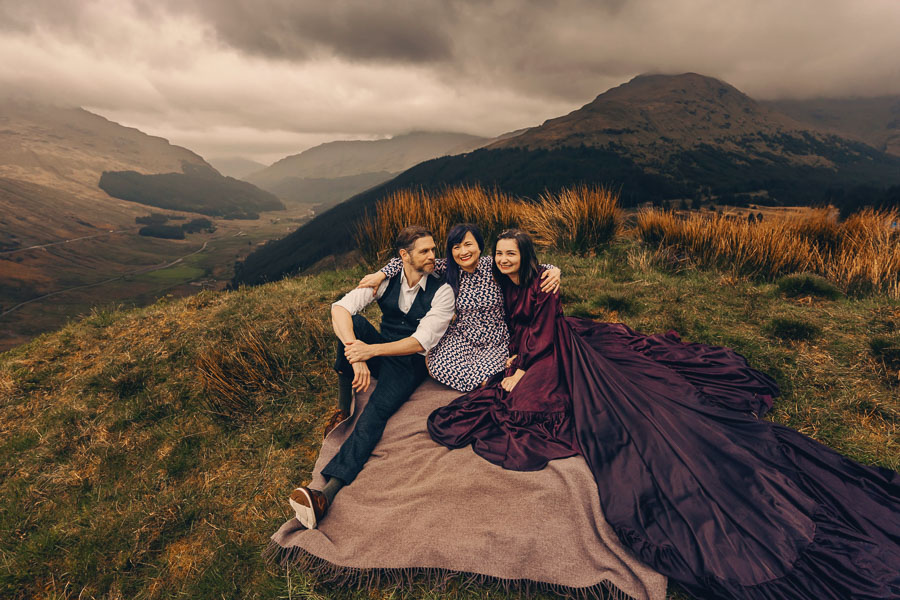 Three people sitting on a blanket.