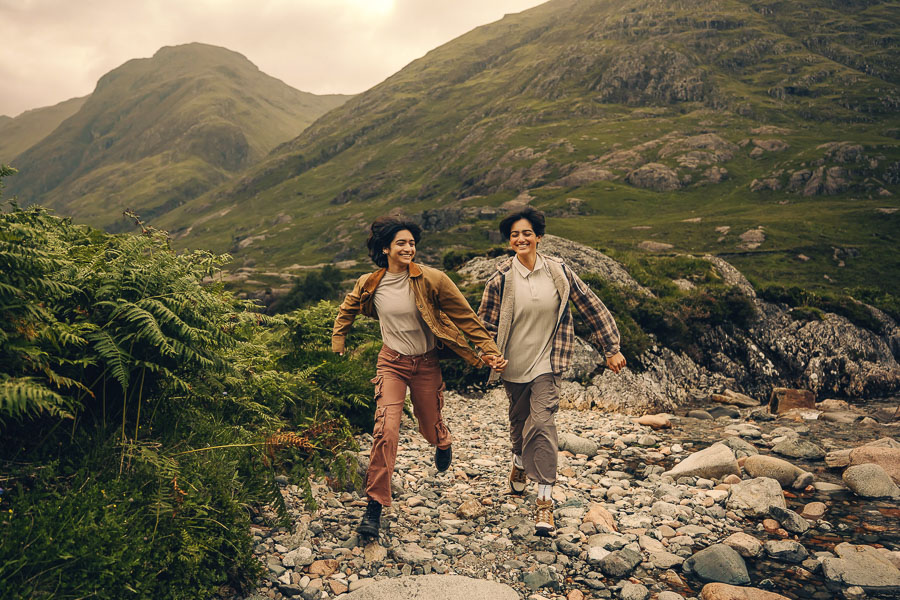 Two people running through rocky landscape.