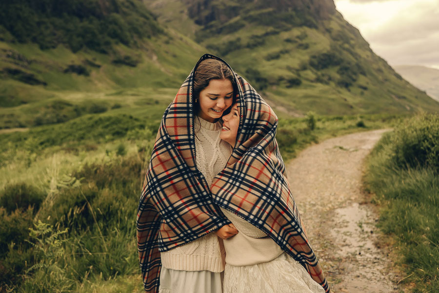 Two children wrapped in tartan blanket.