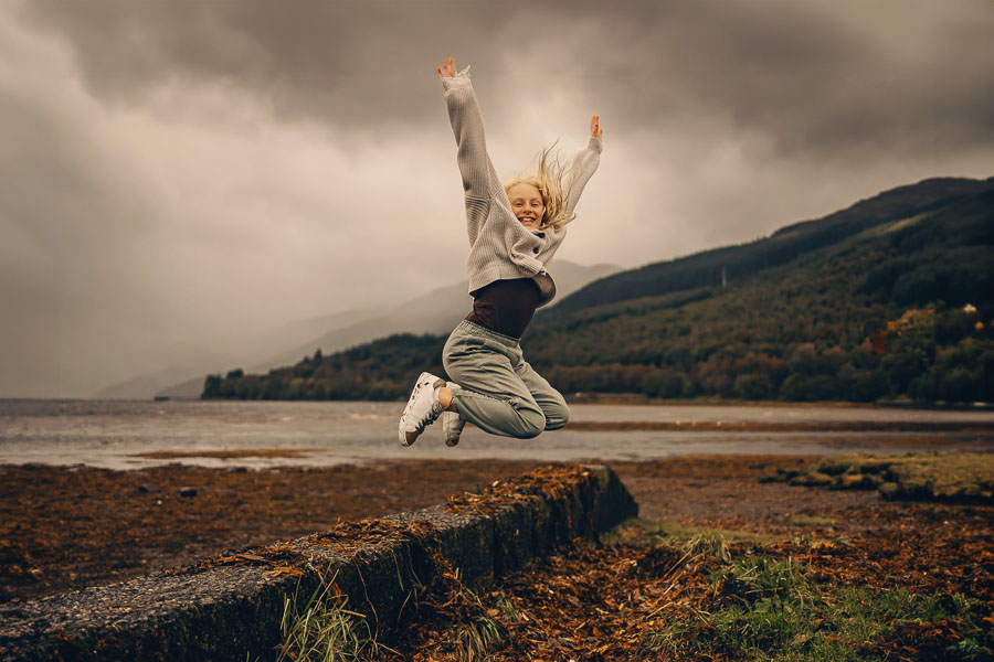 Person jumping against dramatic cloudy backdrop.