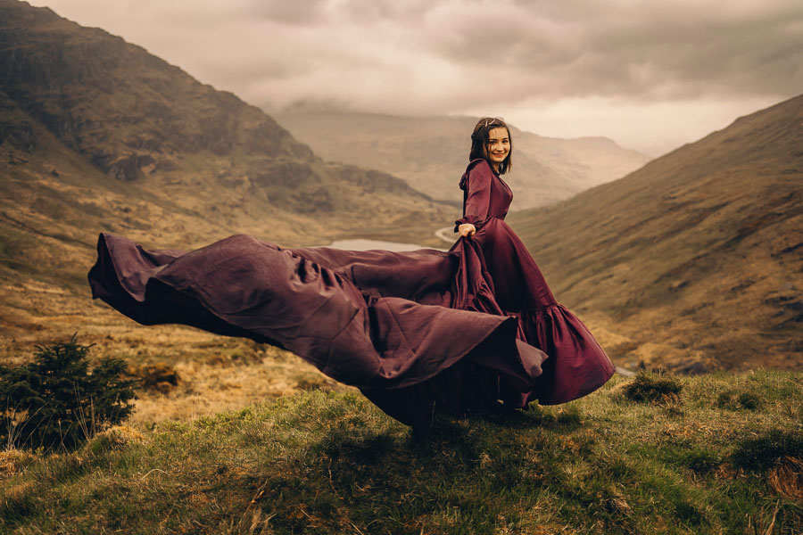 Woman in flowing dress on hillside.