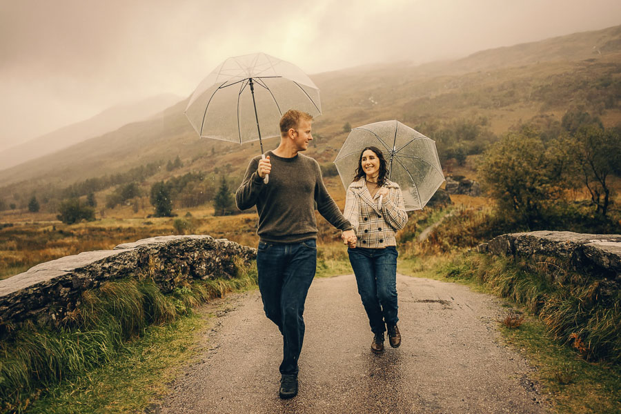 Couple walking with umbrellas in rain.
