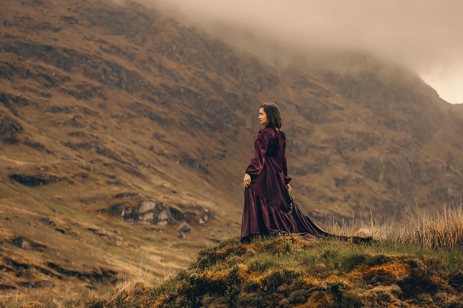 Woman in purple dress on hillside.