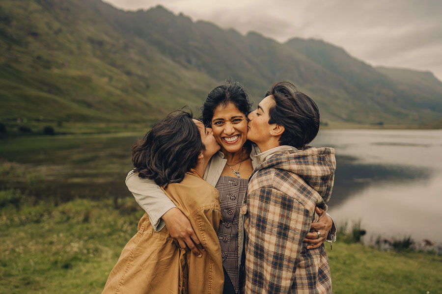 Three people embracing by a lake.