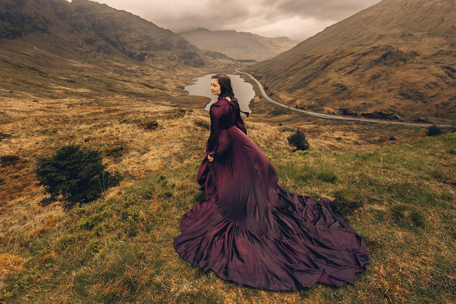 Woman in purple dress overlooking landscape.