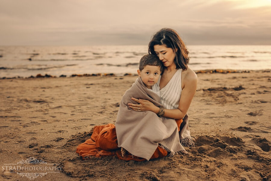 mother cuddling her son at the beach