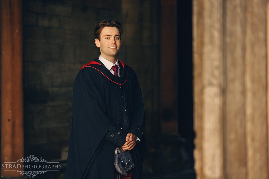 Graduate in academic gown standing proudly.