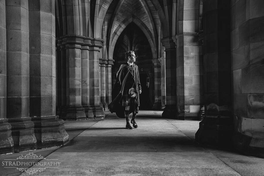 Graduate walking through historic arches.