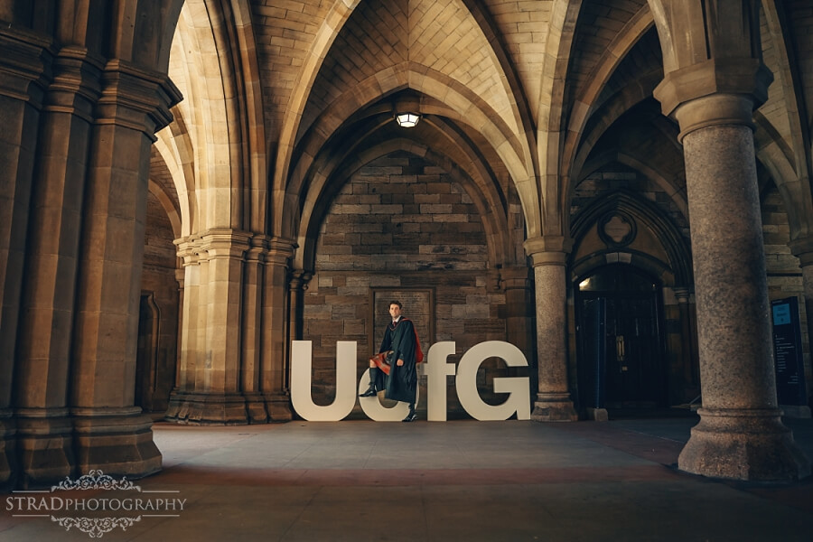 Graduate posing with University of Glasgow sign