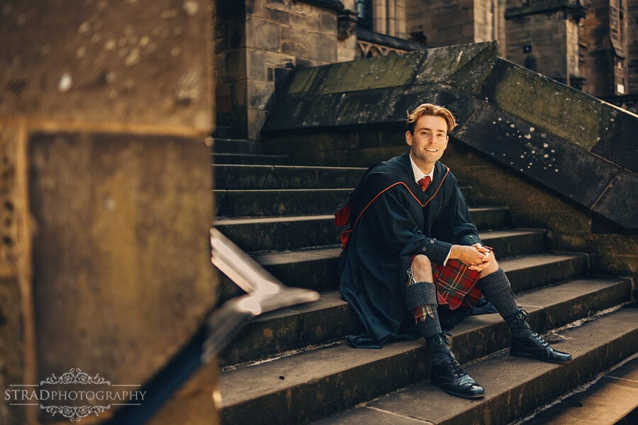 Graduate seated on stone steps.