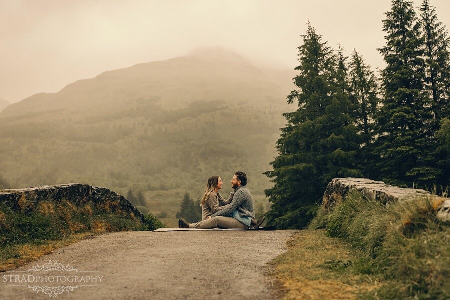 couple sitting in front one another on the bridge