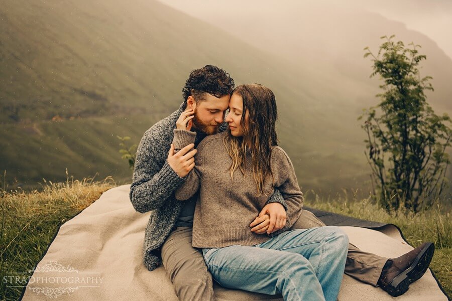 couple sitting on the blanket in the rain in Scottish highlands