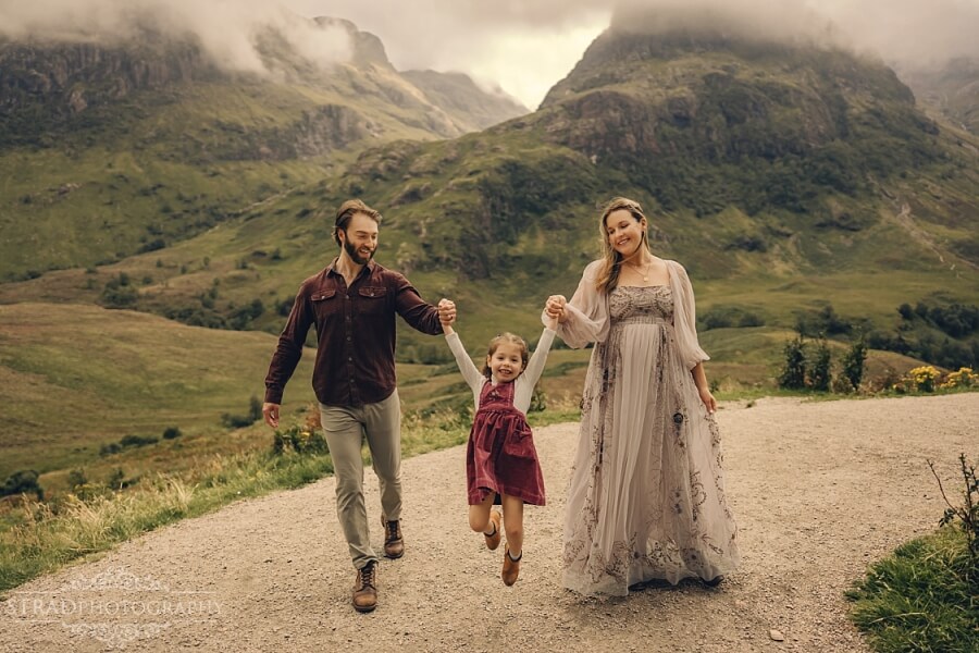 Parents swinging their daughter in a scenic mountain walk. during maternity photography Glencoe session.