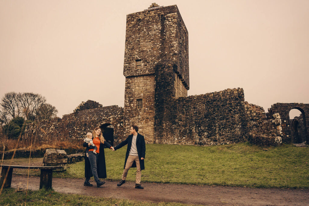 Family of three walking in front of Mugdock Castle. 