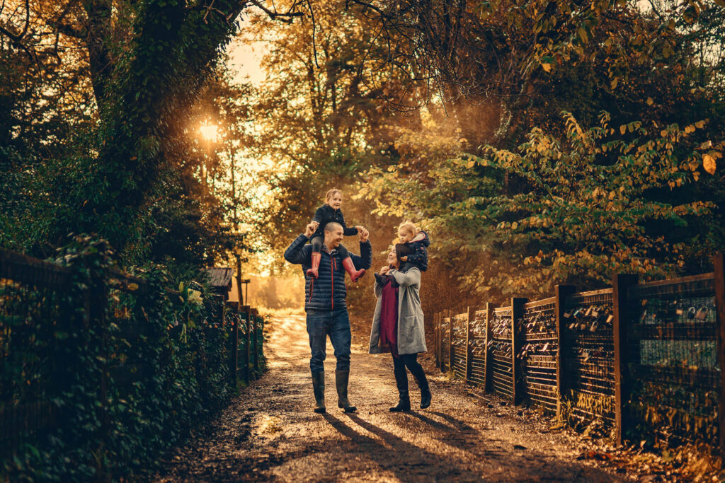 Parents carrying their daughters on their shoulders near the waterfall in Rouken Glen Park.