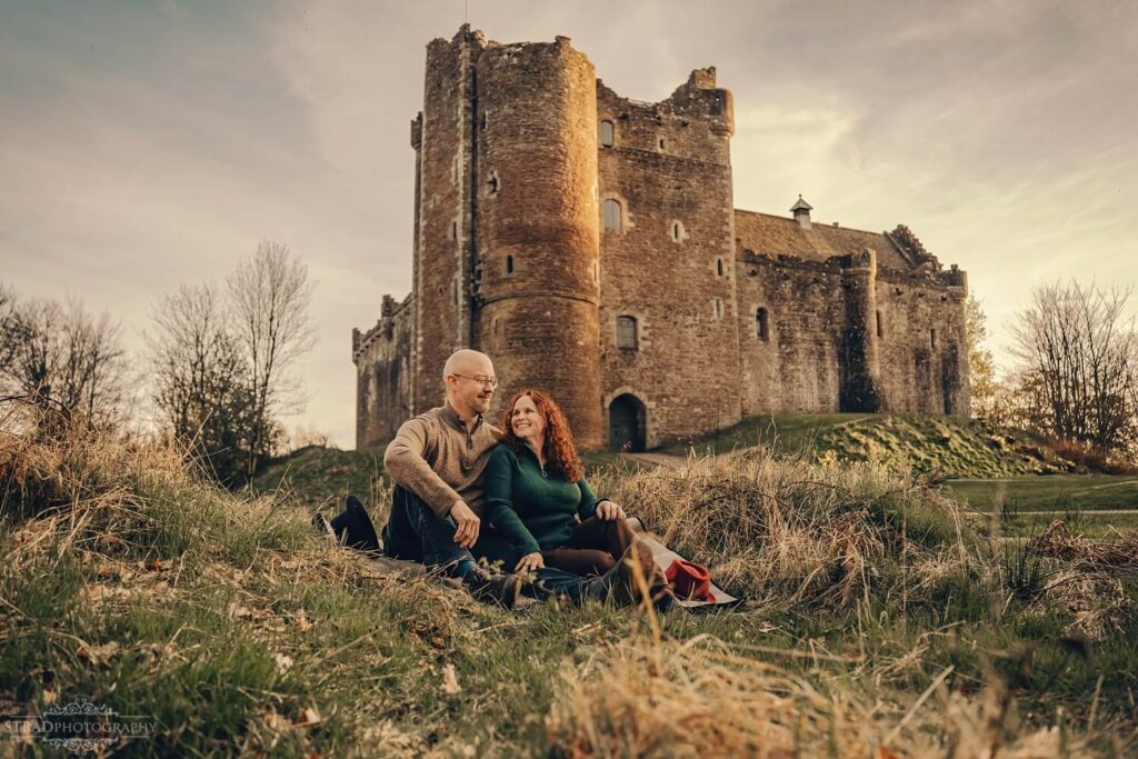 Couple sitting near historic castle.