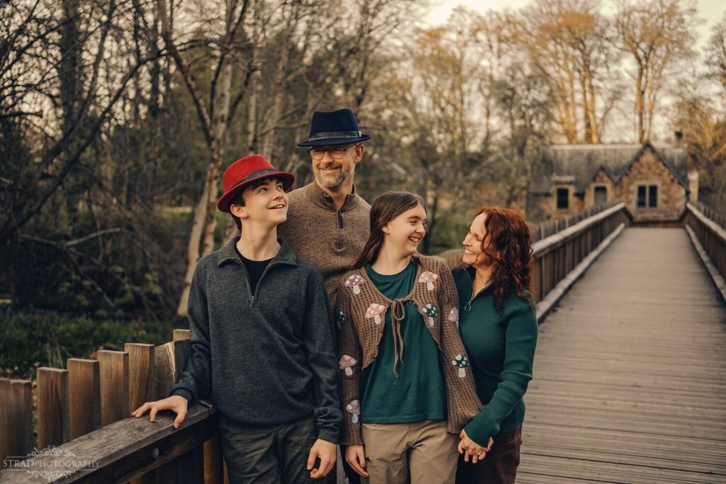 Family posing on a wooden bridge.