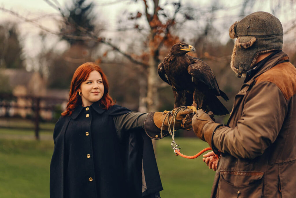 Person holding eagle in outdoor setting.
