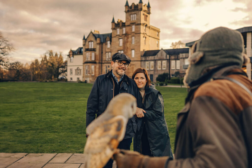 Couple with owl near historic building.