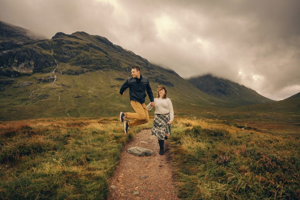 Couple joyfully jumping on a path.