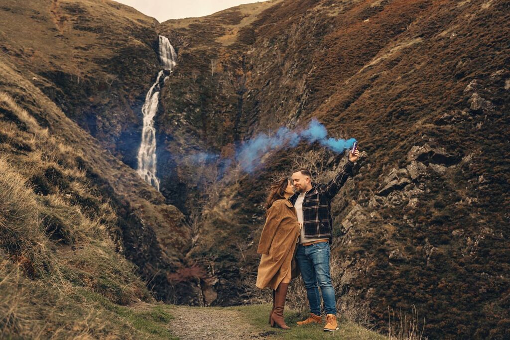 Couple celebrating with blue smoke outdoors.