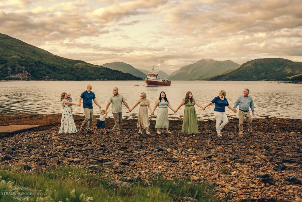 Extended family walking together along the shoreline at Loch Etive