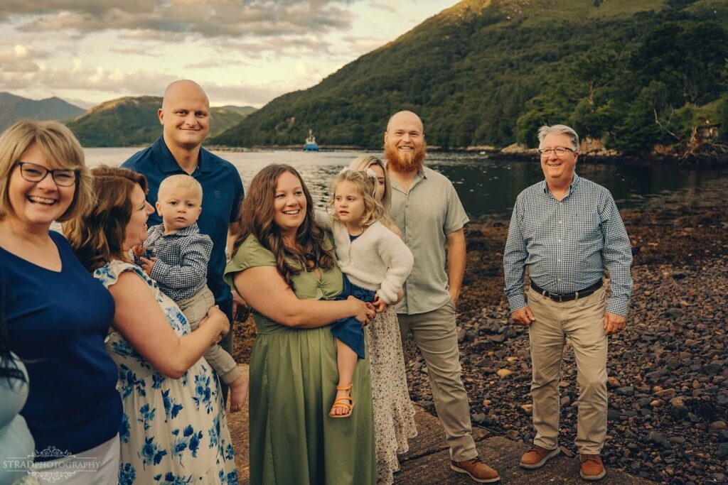 Extended family playing a telephone game at the shore of Loch Etive